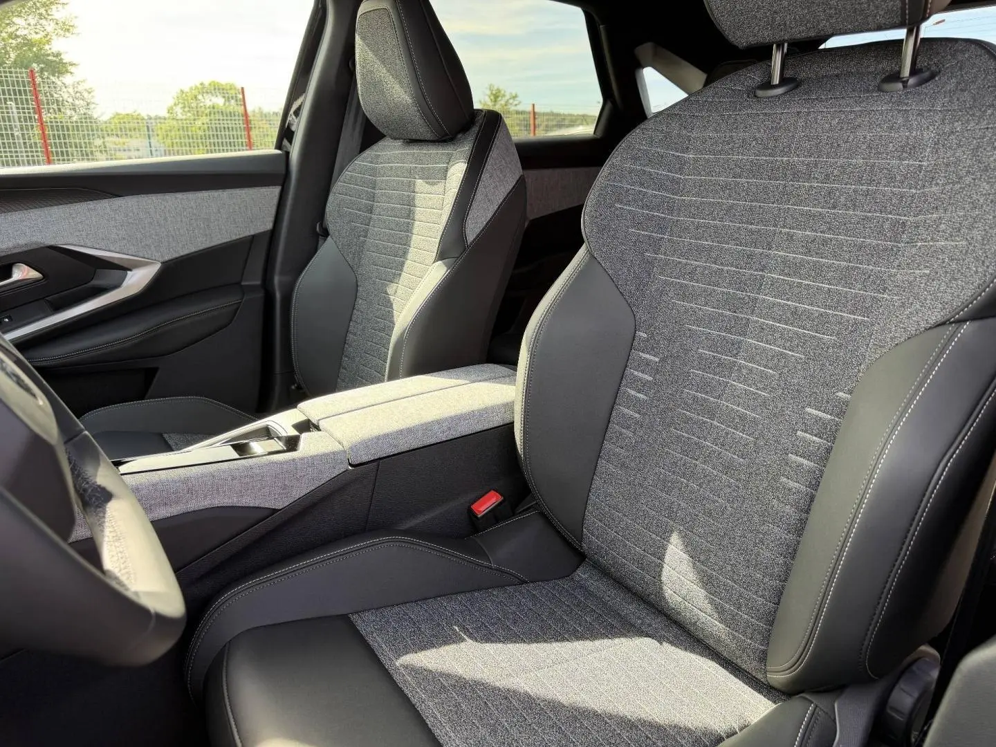 Vue intérieure rapprochée des sièges avant gris tissu et cuir du Peugeot 3008 Hybrid noir Perla Nera 2026.