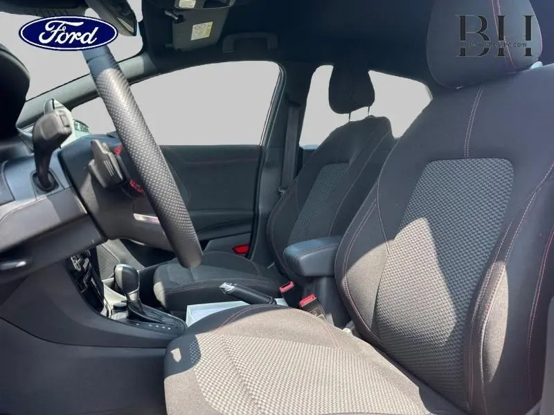 Vue intérieure côté conducteur du Ford Puma 2022, sièges sport noirs avec surpiqûres rouges et volant multifonction.
