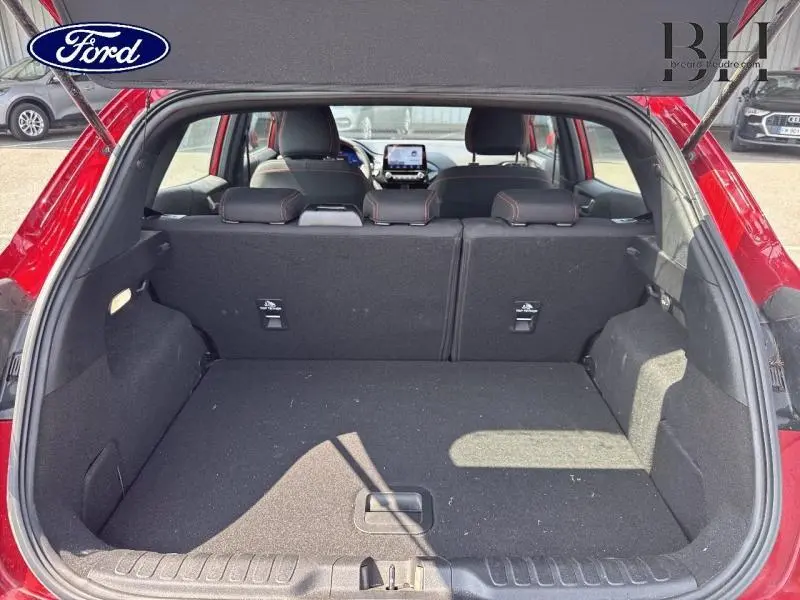 Vue arrière du coffre spacieux d'une Ford Puma rouge, banquette arrière noire avec surpiqûres rouges visible à l'intérieur.