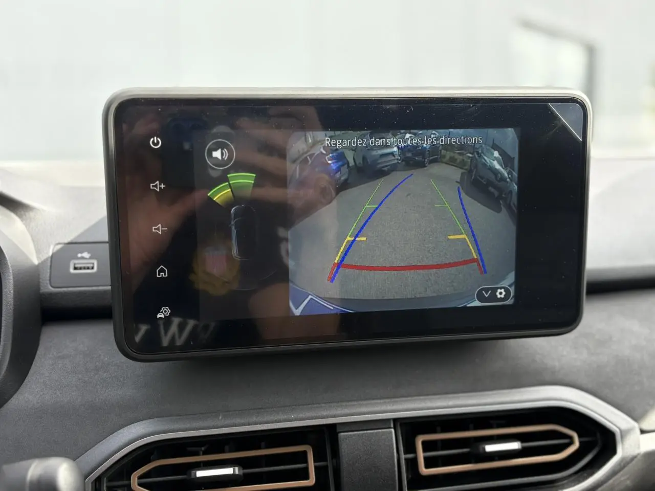 Écran tactile intérieur montrant la caméra de recul du Dacia Jogger Gris Schiste avec lignes de guidage colorées.