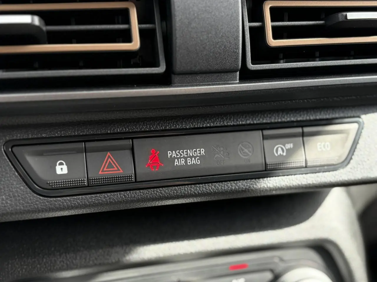 Gros plan sur la console centrale du Dacia Jogger gris, montrant les voyants de sécurité et mode ECO.
