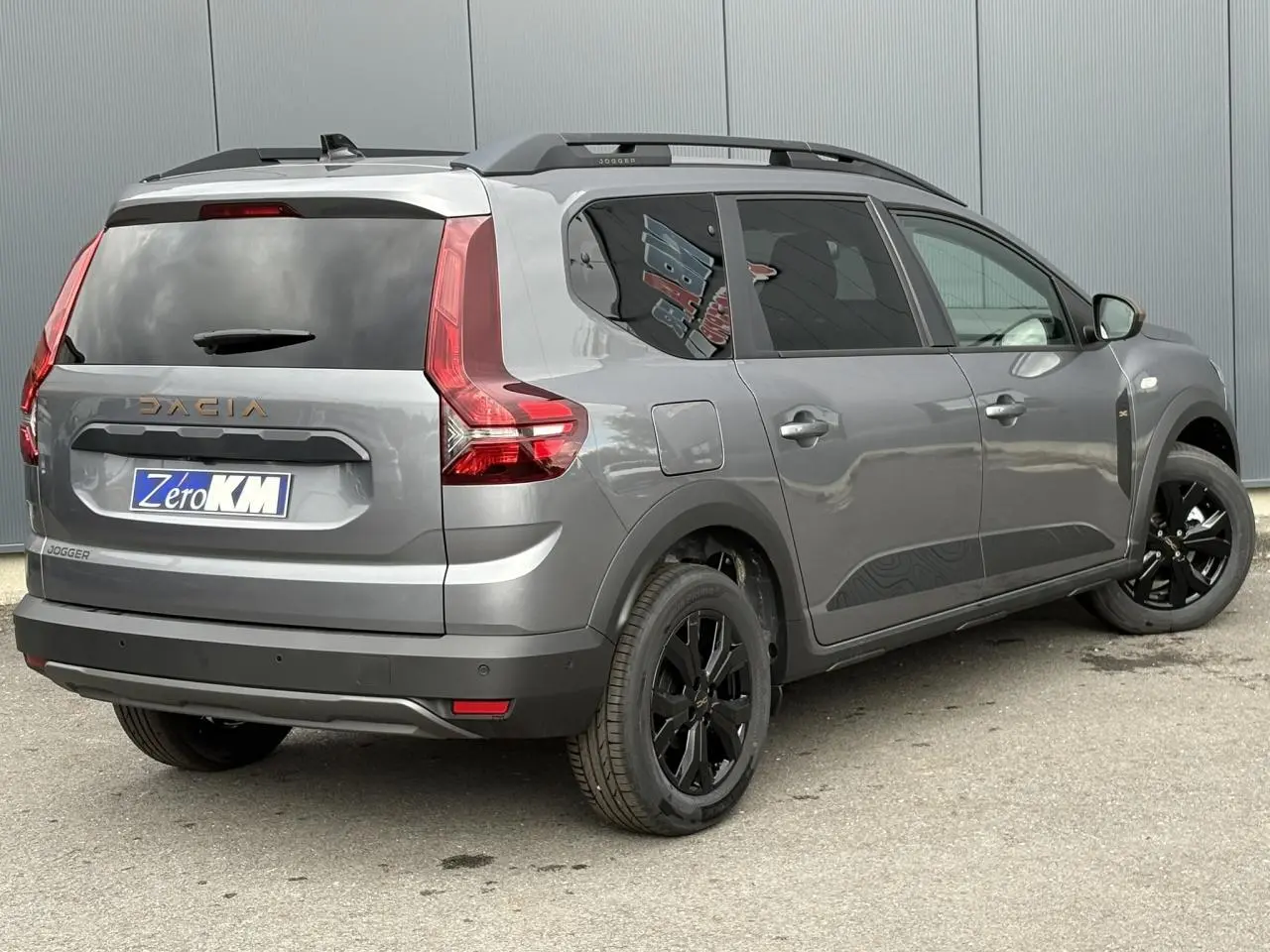 Vue 3/4 arrière droite du Dacia Jogger gris schiste avec jantes noires et vitres arrière surteintées.