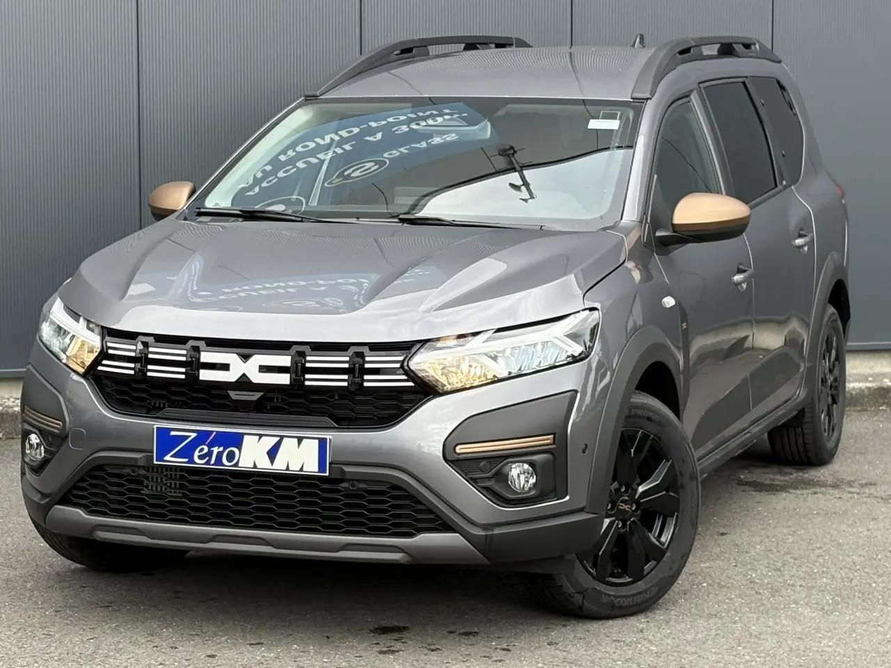 Vue 3/4 avant d'un Dacia Jogger gris schiste avec rétroviseurs bronze et jantes noires en aluminium.