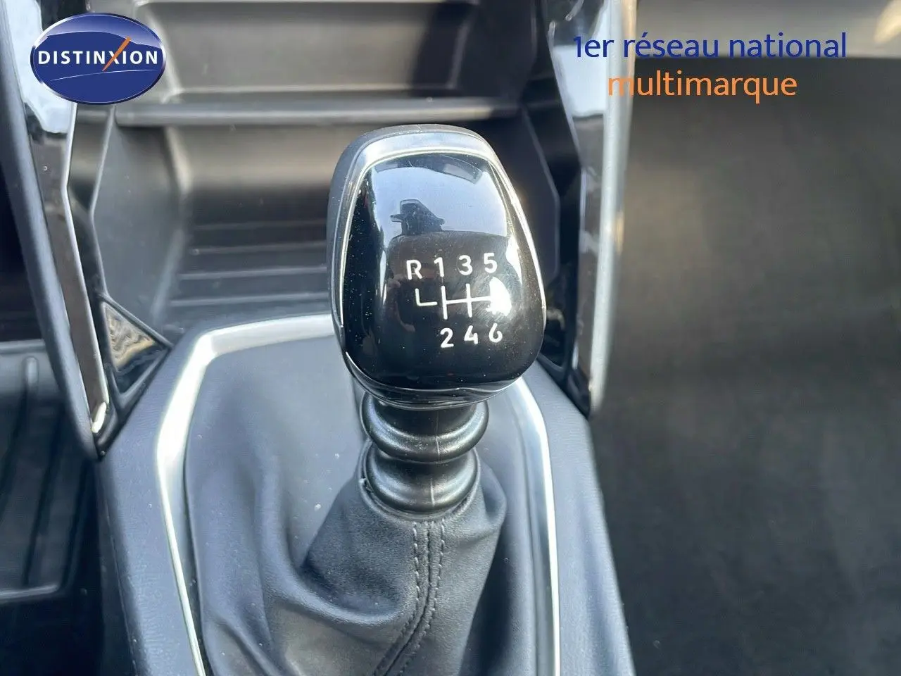 Gros plan sur le levier de vitesses manuel noir de la Peugeot 208 blanche, montrant la grille des 6 rapports et la marche arrière.