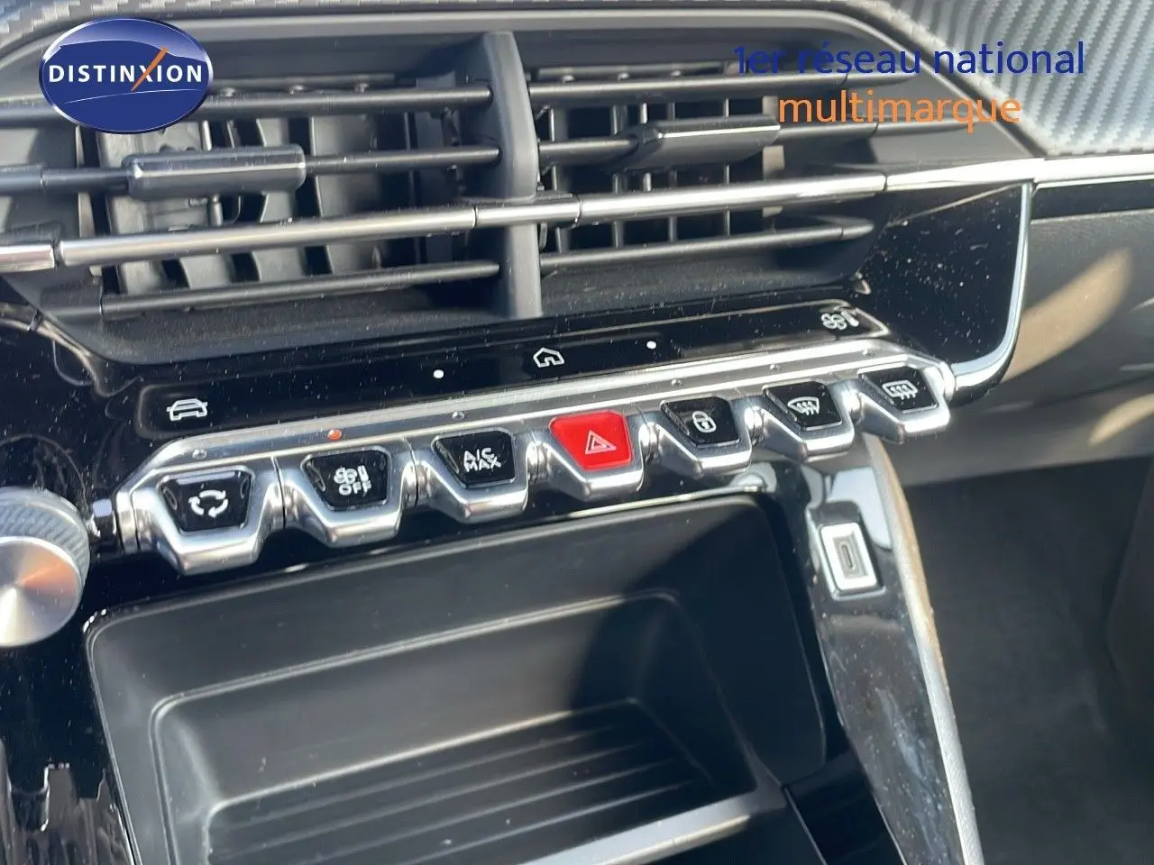 Gros plan sur la console centrale de la Peugeot 208 blanche, montrant les boutons de commande et les aérateurs.