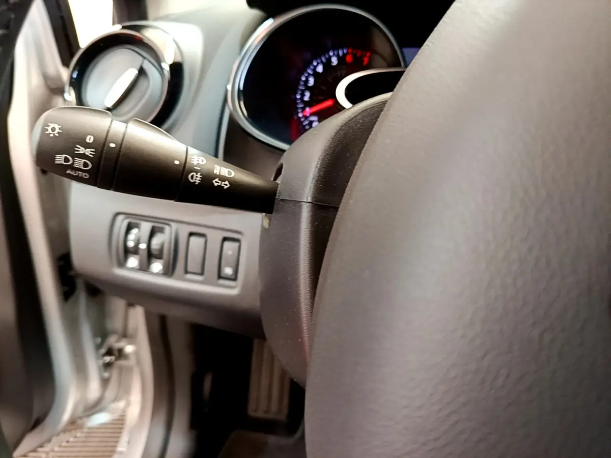 Gros plan sur la manette des phares à gauche du volant cuir dans l’habitacle gris clair de la Renault Clio Business TCe 90 2019.