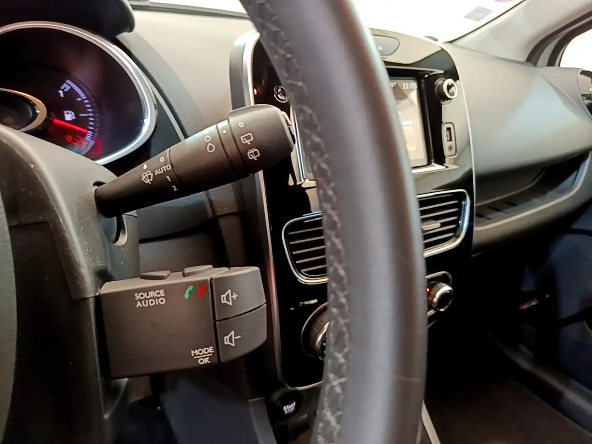 Détail intérieur du volant cuir et commandes audio de la Renault Clio Business TCe 90 2019, tableau de bord et écran tactile visibles.