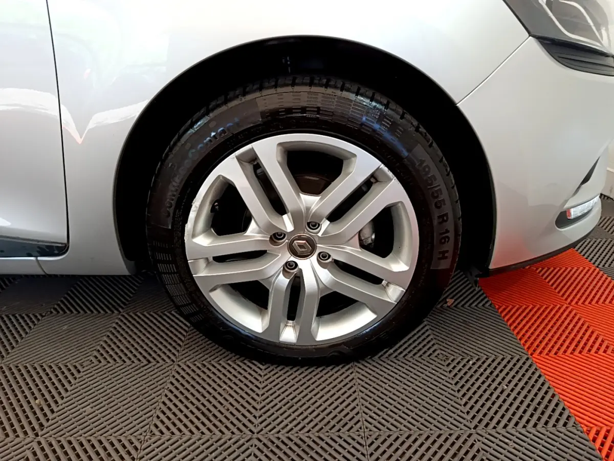 Gros plan sur la roue avant droite gris clair d'une Renault Clio Business TCe 90 avec jante alliage et logo Renault central.