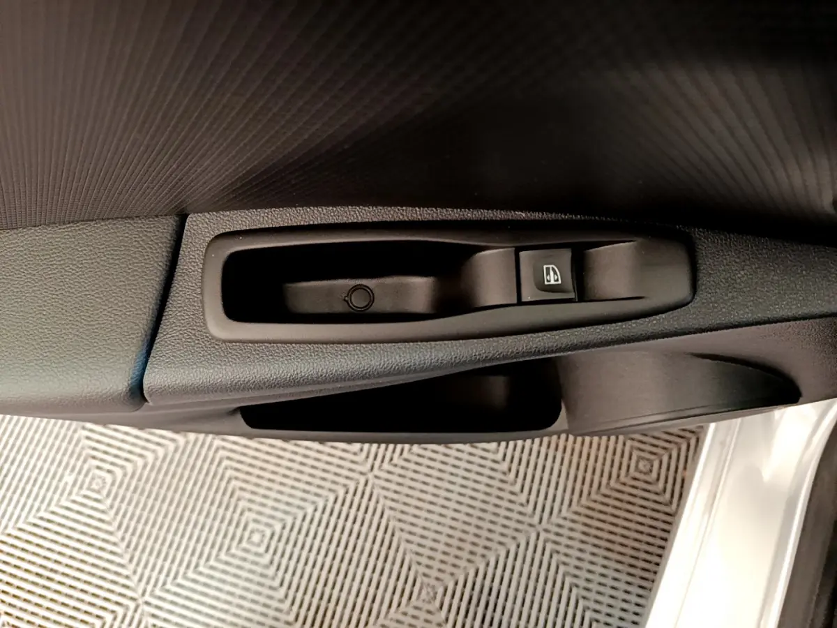 Gros plan sur la commande de lève-vitre côté conducteur d'une Renault Clio Business TCe 90 gris clair, intérieur noir.