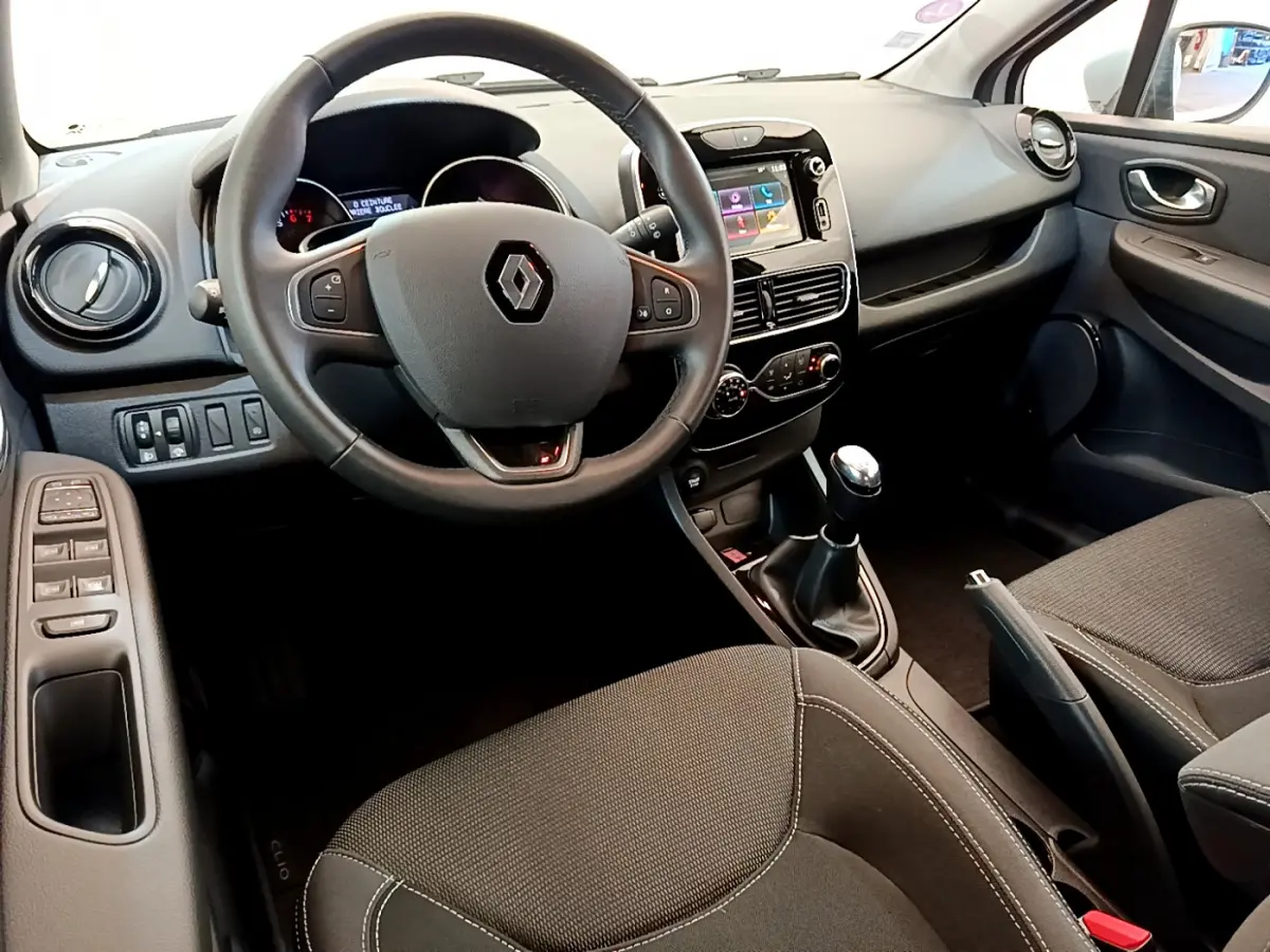 Intérieur de Renault Clio Business TCe 90 2019 vu côté conducteur, volant cuir, écran tactile et boîte manuelle visibles.