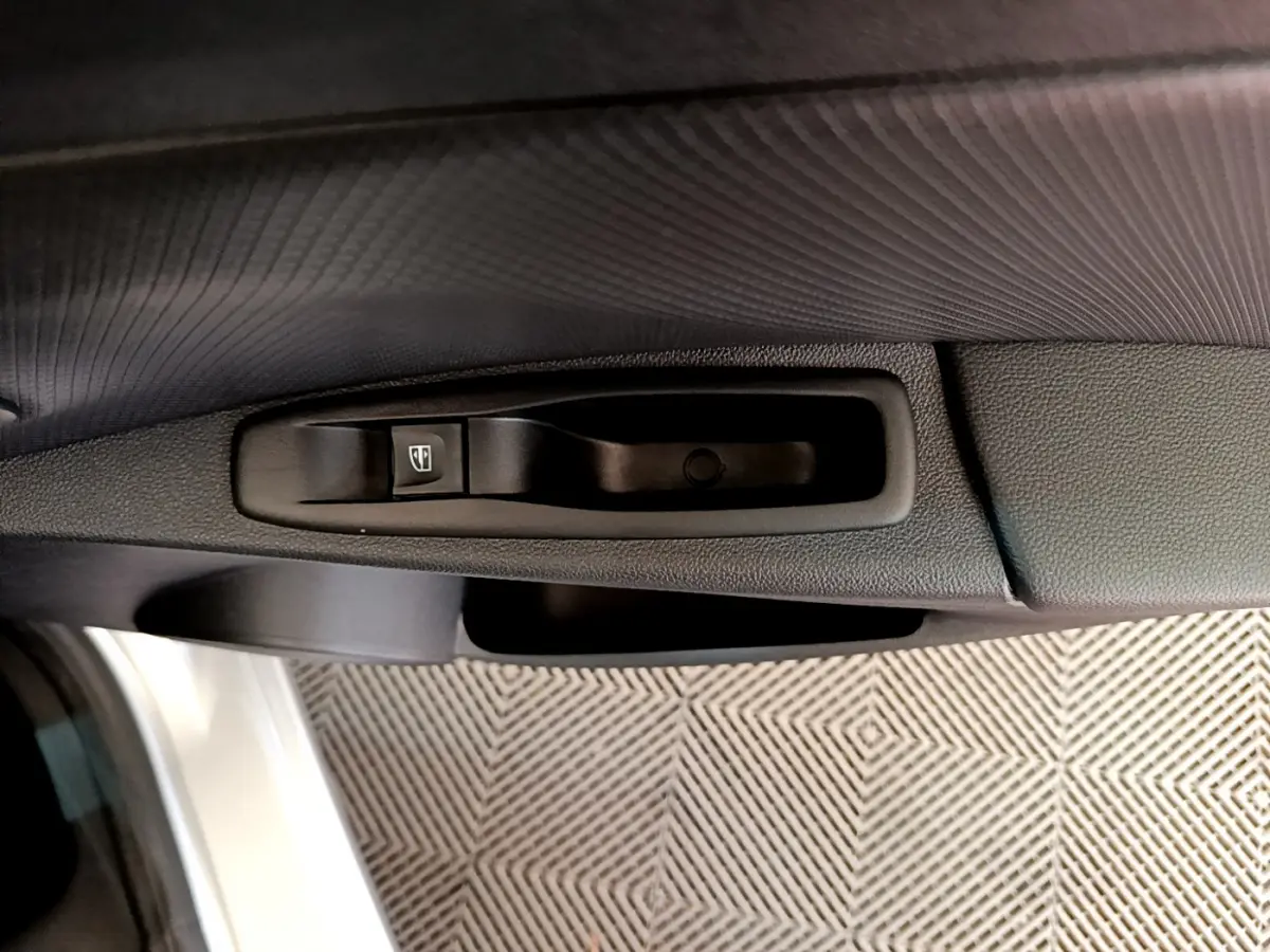 Poignée intérieure et bouton de commande de vitre sur la portière côté gauche d'une Renault Clio Business gris clair 2019.
