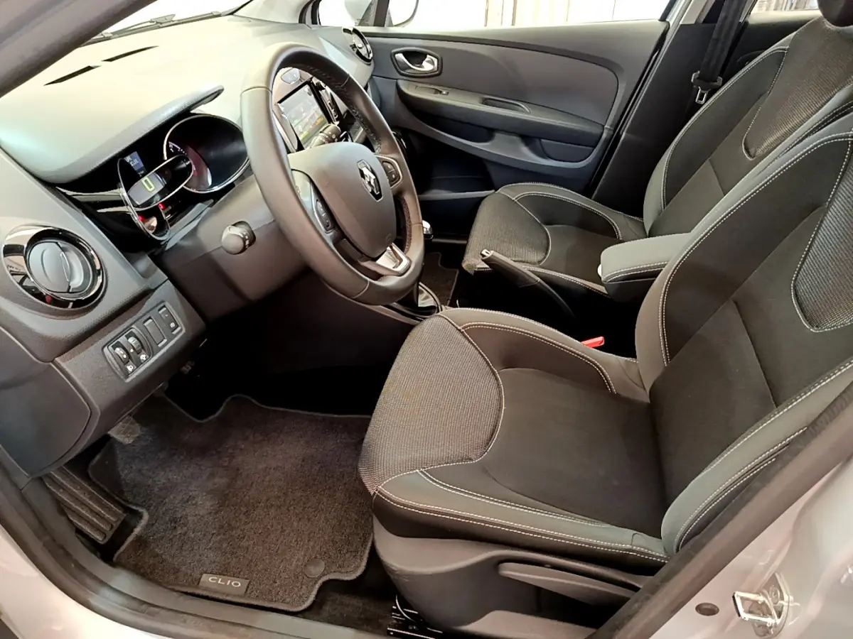 Vue intérieure côté conducteur de la Renault Clio Business TCe 90 2019 avec sièges noirs et volant cuir multifonctions.