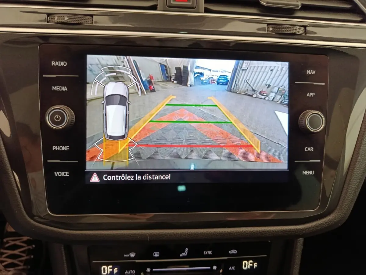 Vue rapprochée de l'écran tactile du tableau de bord affichant la caméra de recul avec guidage couleur du Volkswagen Tiguan noir.