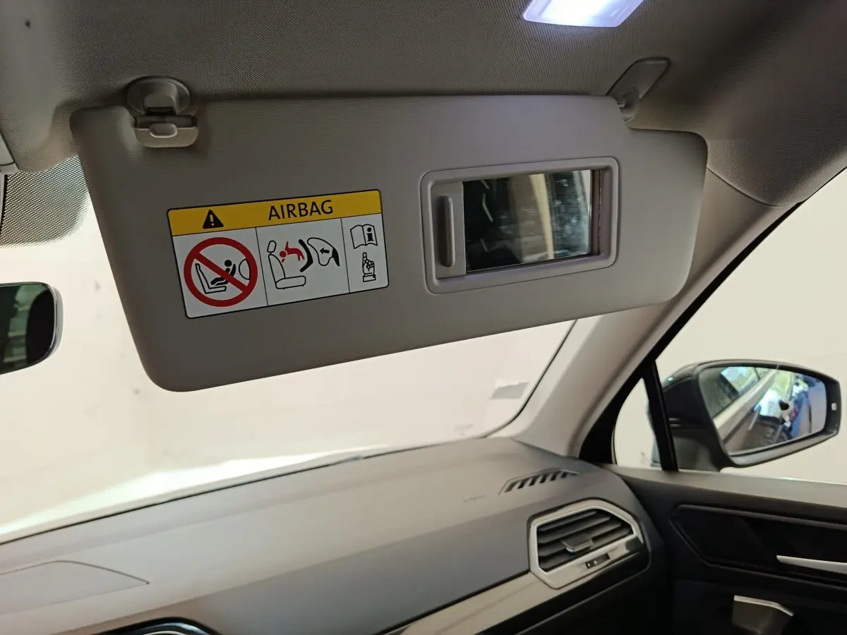 Intérieur du Volkswagen Tiguan 2022 noir, vue côté passager avec pare-soleil abaissé et miroir intégré.