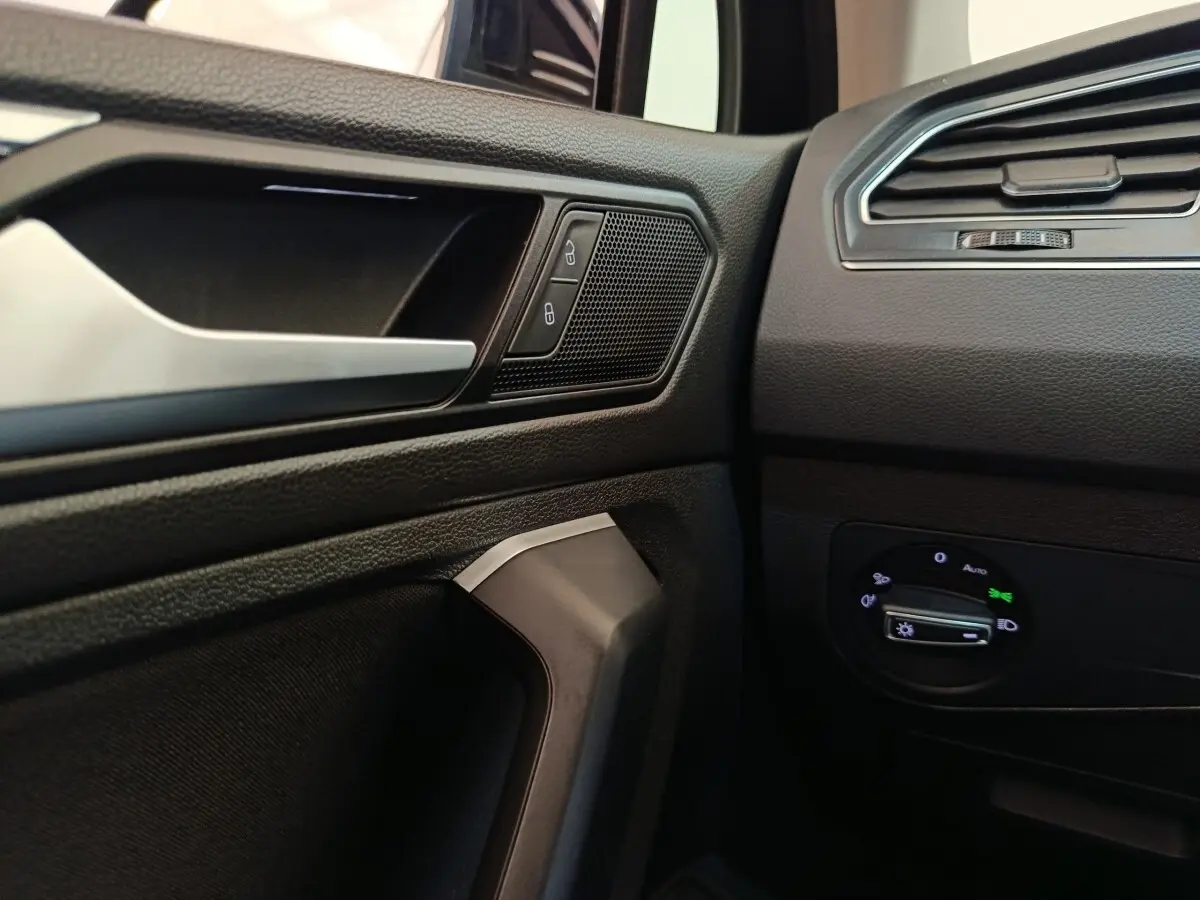 Détail intérieur côté conducteur du Volkswagen Tiguan 2022 noir, avec commandes de verrouillage et réglage phares.