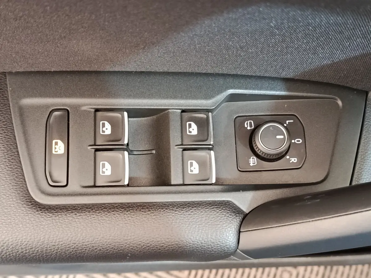 Gros plan sur les commandes de lève-vitres et réglage des rétroviseurs côté conducteur du Volkswagen Tiguan noir 2022.