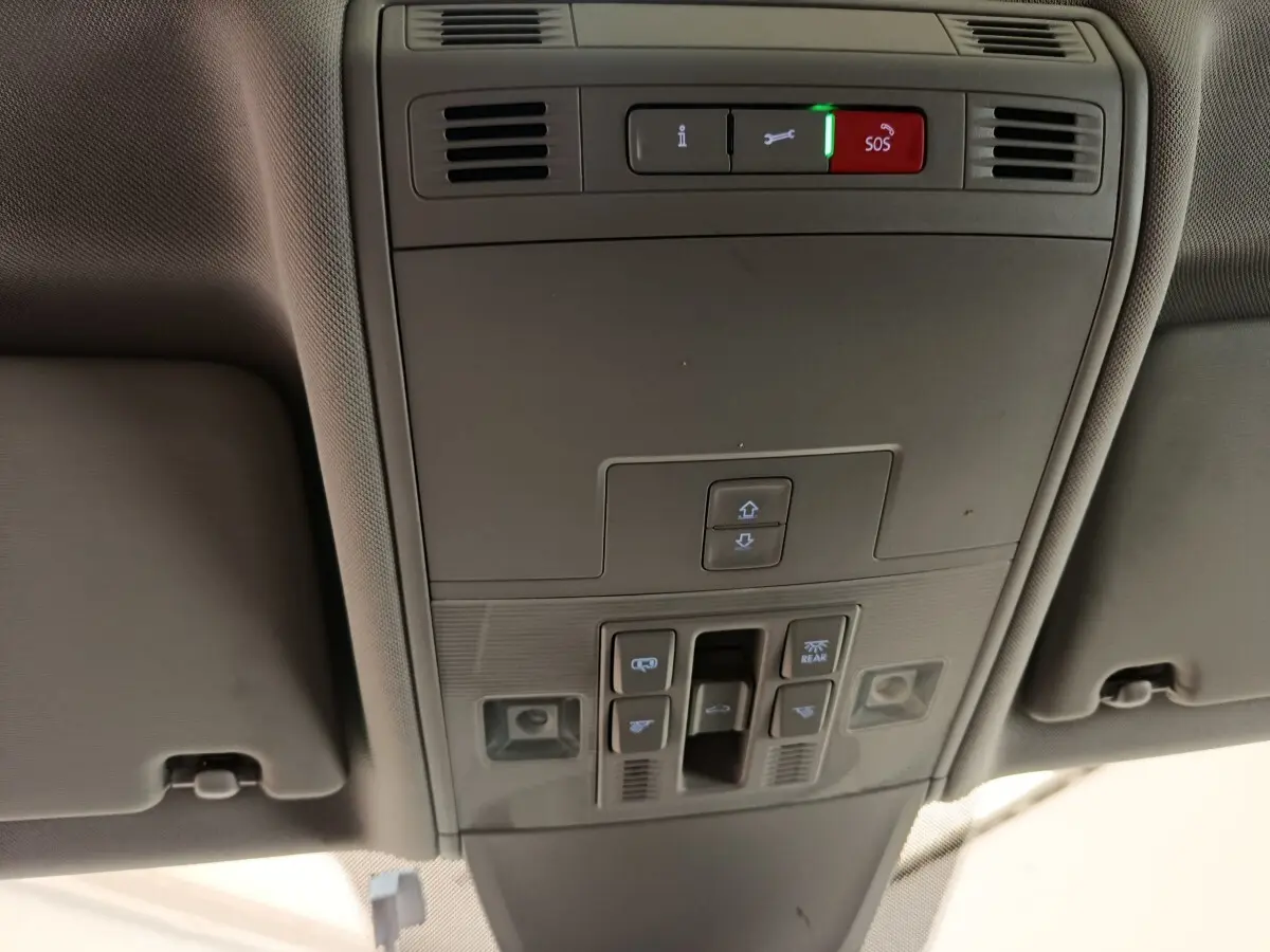 Vue en contre-plongée du panneau de commandes de toit intérieur gris du Volkswagen Tiguan 2022, avec boutons SOS et éclairage.