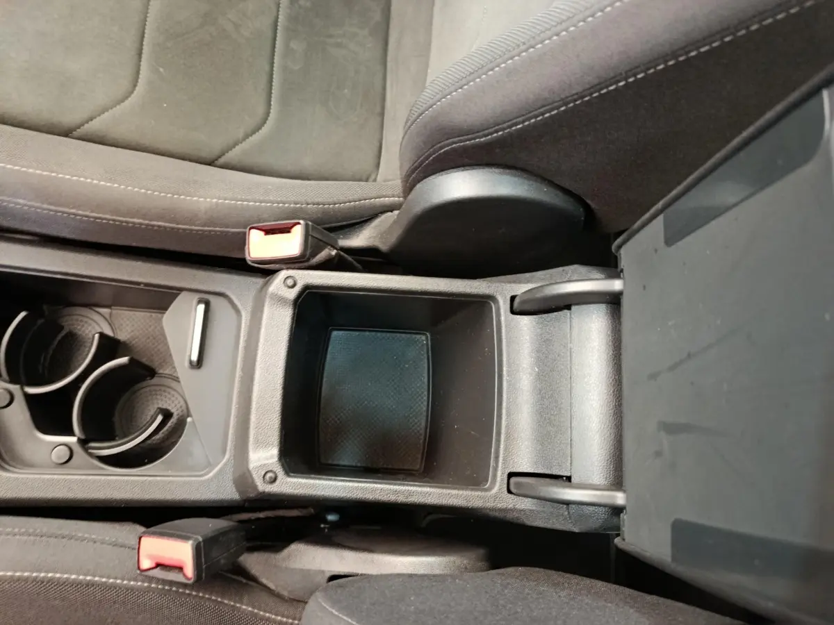Vue rapprochée de la console centrale noire du Volkswagen Tiguan 2.0 TDI 150 DSG7 Elegance avec porte-gobelets et rangement ouvert.