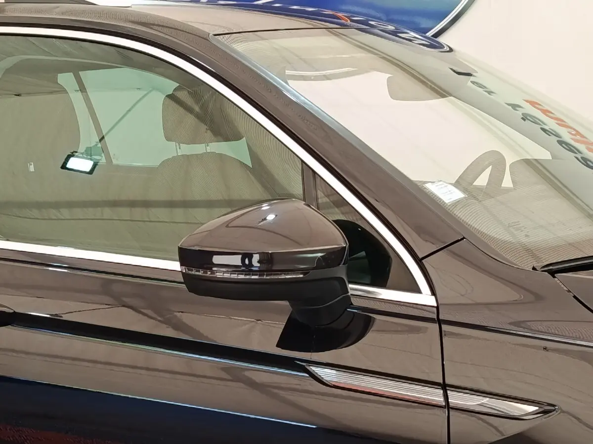 Gros plan sur le rétroviseur côté conducteur d’un Volkswagen Tiguan noir 2022 avec finition élégante et détails chromés.