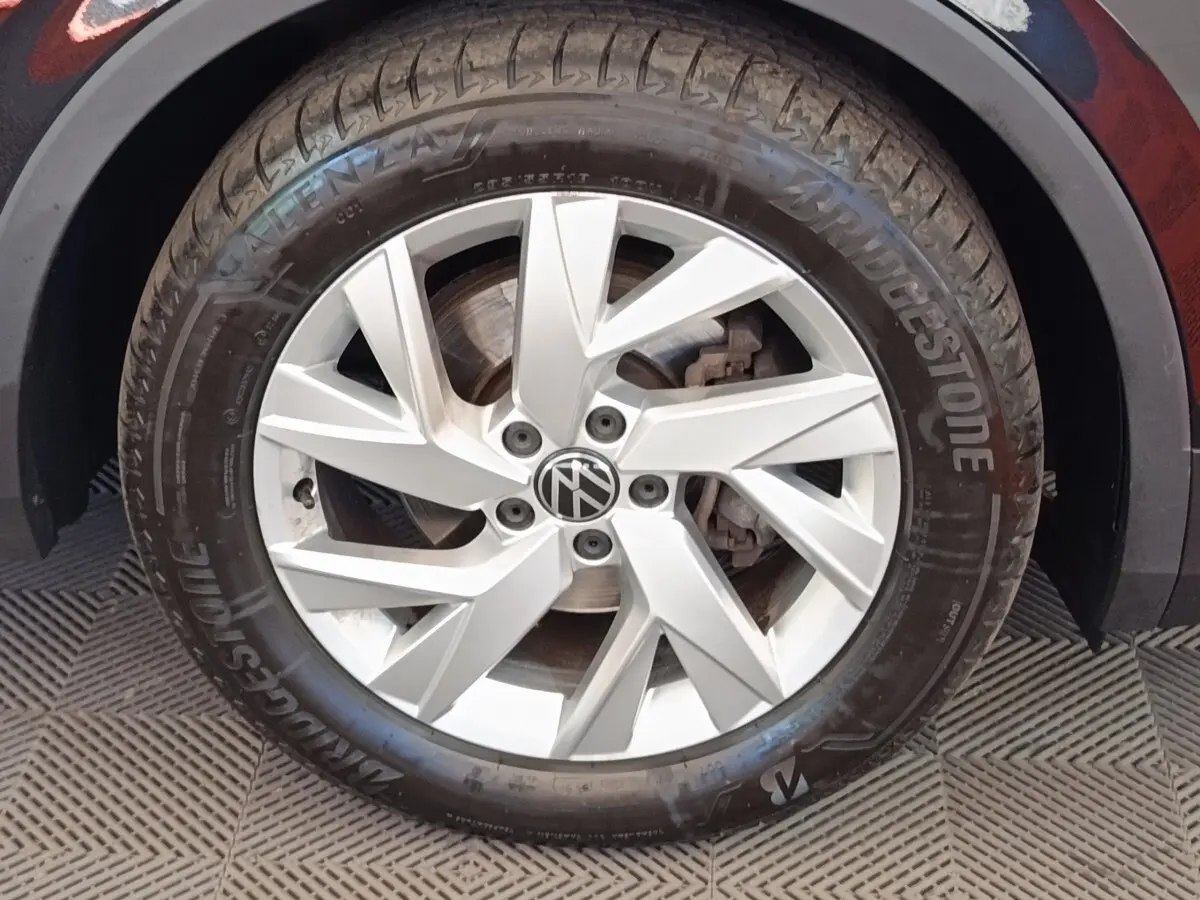 Gros plan sur la roue avant droite du Volkswagen Tiguan noir, jante alliage argentée avec logo VW central.