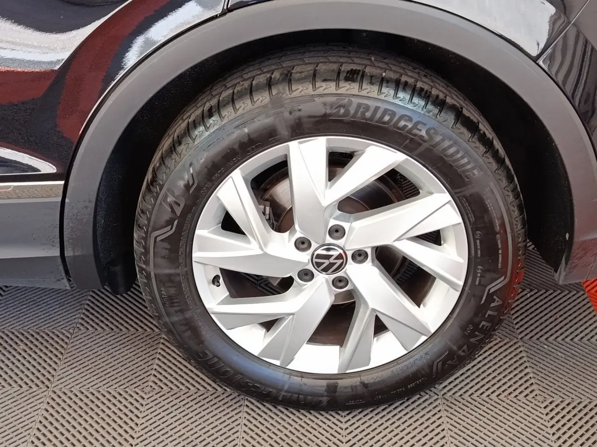 Gros plan sur la roue avant droite d’un Volkswagen Tiguan noir, jante alliage argentée à design moderne.
