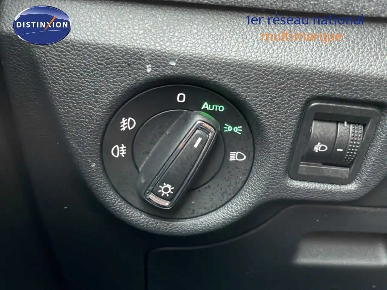 Gros plan sur la commande des phares du Skoda Kamiq 2025, avec réglage automatique activé sur fond noir texturé.