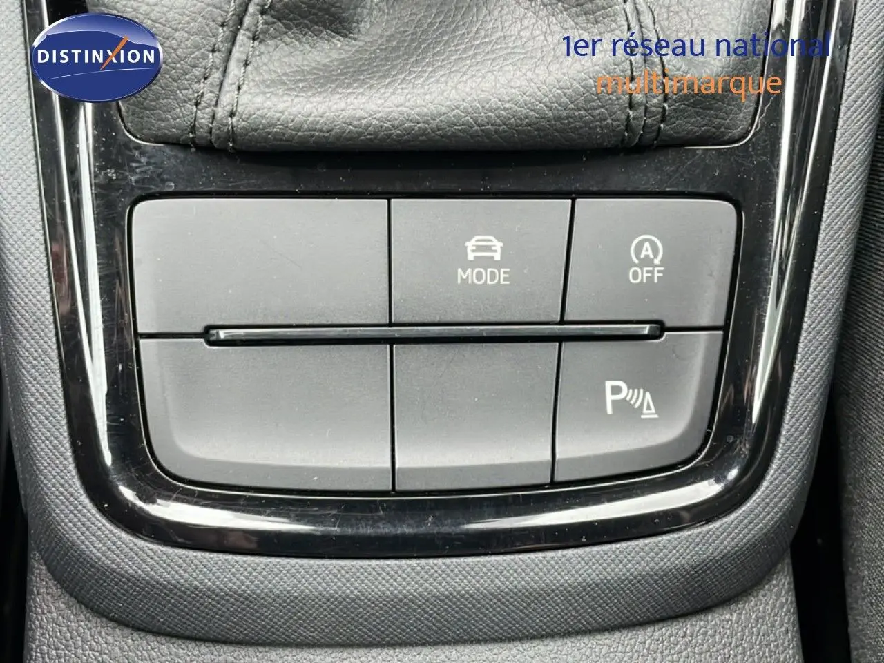 Gros plan sur les boutons de commande du mode de conduite et assistance au stationnement dans une Skoda Kamiq blanc glacier 2025.
