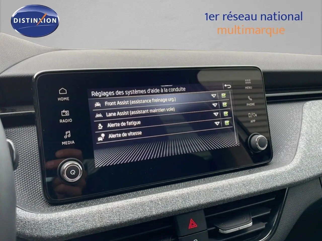Écran tactile du tableau de bord du Skoda Kamiq blanc glacier, affichant les réglages d’aides à la conduite.