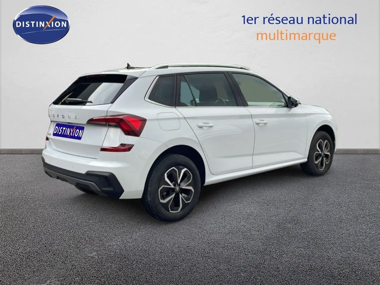 Vue 3/4 arrière droite d'un Skoda Kamiq blanc glacier avec jantes noires et détails rouges aux feux arrière.