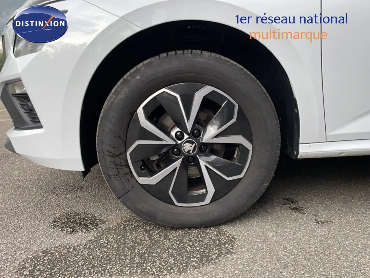 Gros plan sur la roue avant gauche et l'aile d'une Skoda Kamiq blanc glacier, mettant en valeur la jante noire et argentée.