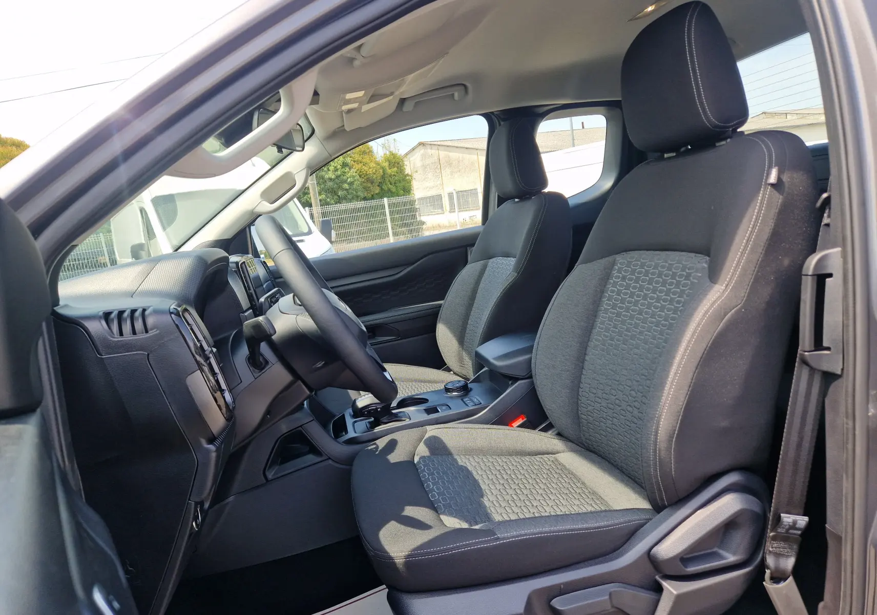Vue intérieure côté gauche du Ford Ranger Super Cabine gris carbone, montrant les sièges avant et le tableau de bord.