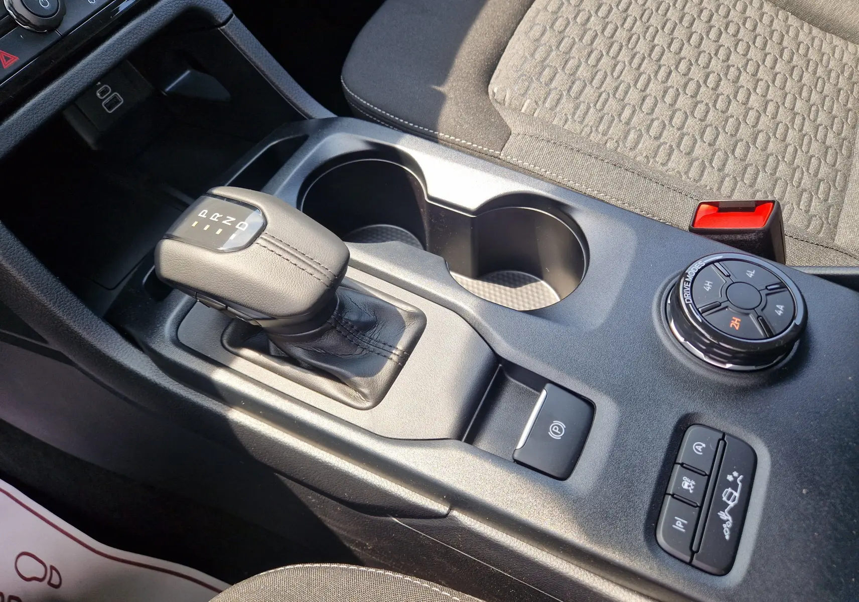 Vue rapprochée de la console centrale intérieure du Ford Ranger Super Cabine gris carbone, avec levier de vitesse automatique et commandes 4x4.