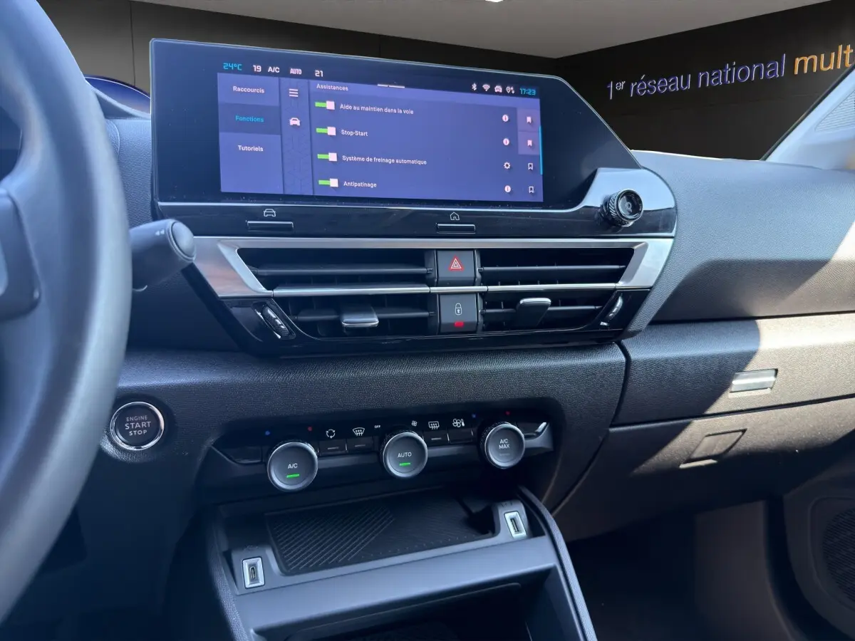 Vue intérieure du tableau de bord de la Citroën C4 2023, écran tactile central et commandes climatisation visibles.