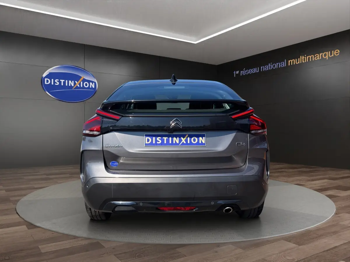 Vue arrière d'une Citroën C4 gris foncé 2023, avec feux LED et logo distinctif sur fond noir.