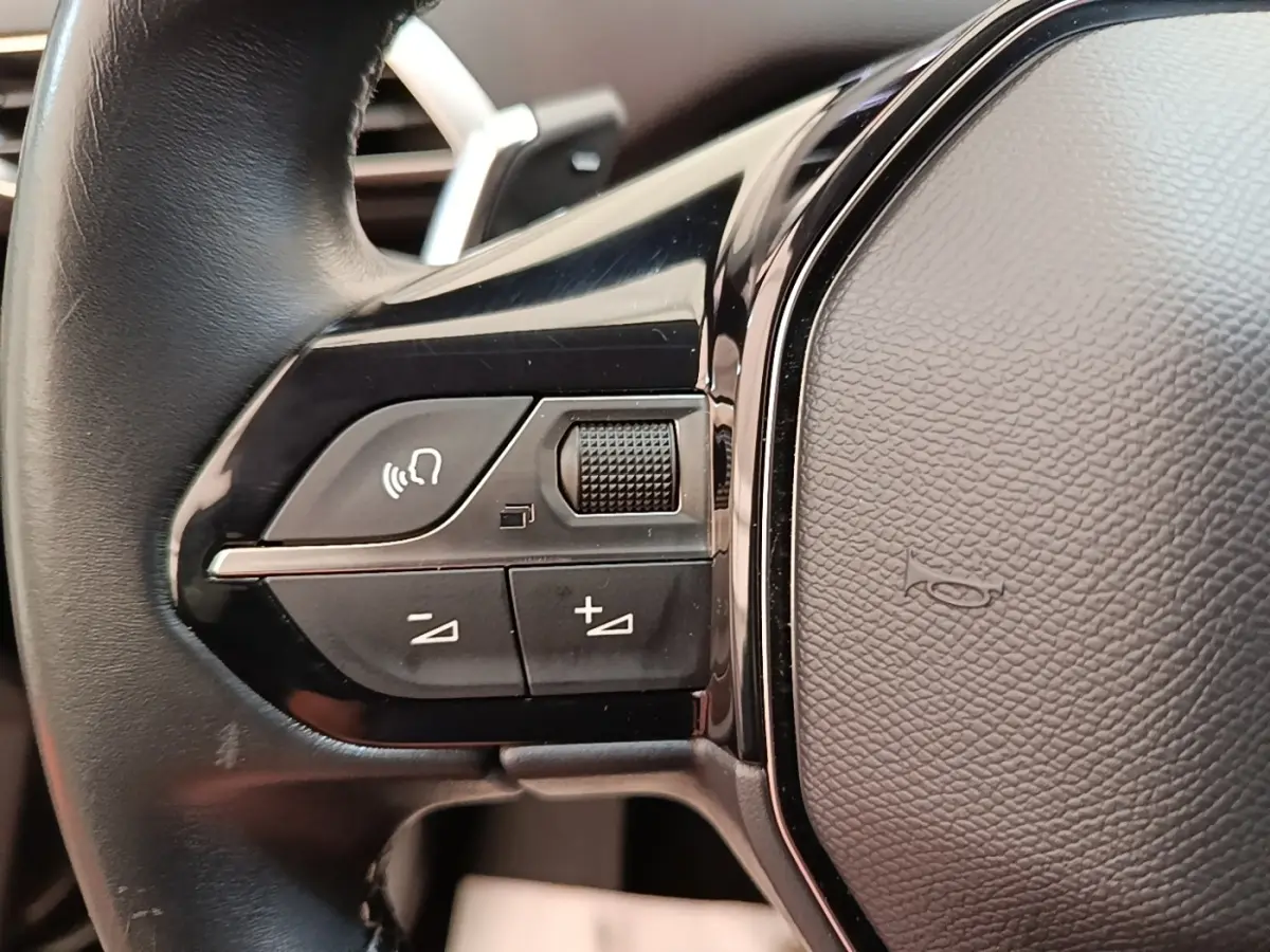 Gros plan sur les commandes gauche du volant cuir noir du Peugeot 3008 PureTech 130 Allure 2022.