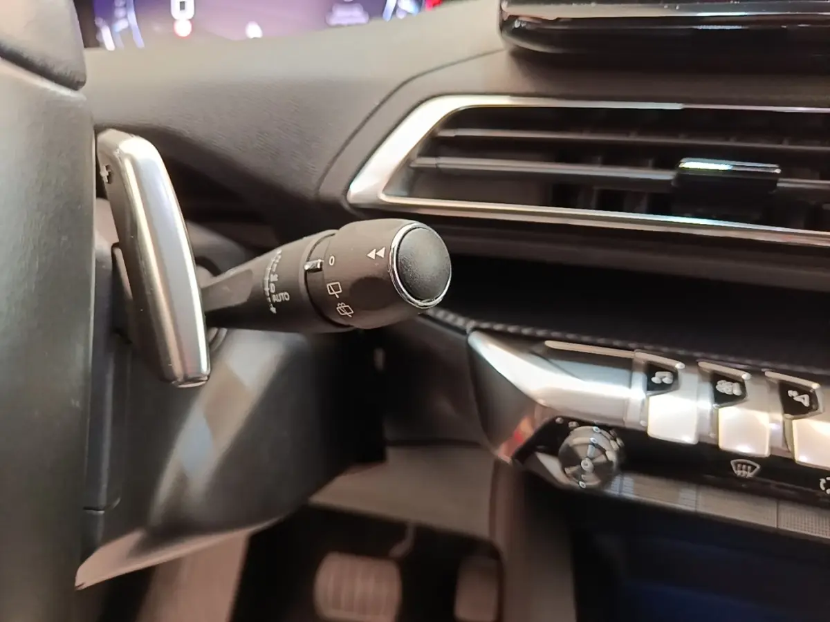 Gros plan intérieur sur la commande d’essuie-glace et la console centrale du Peugeot 3008 noir, version Allure 2022.