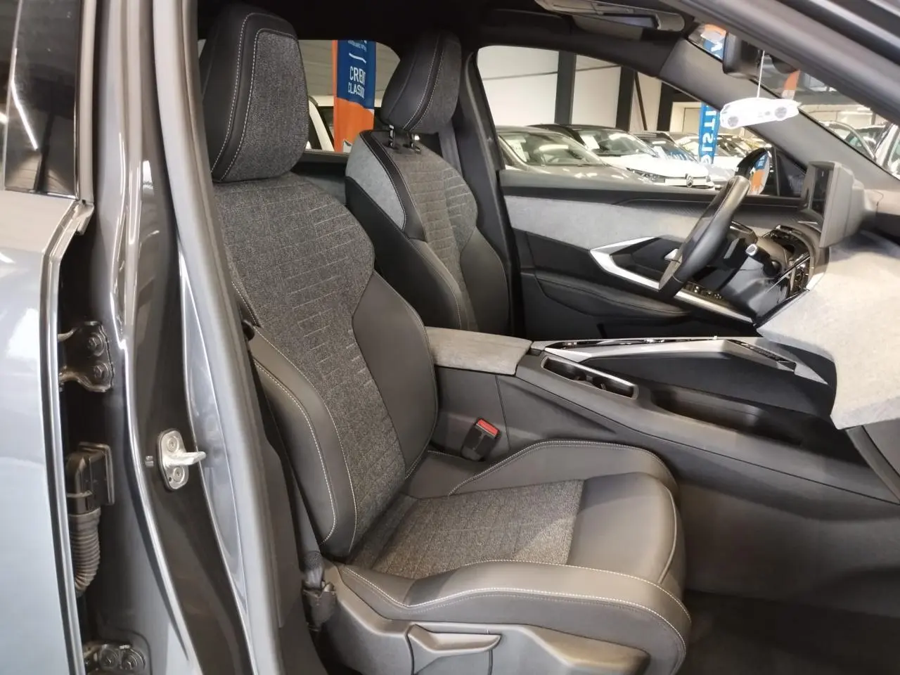Intérieur avant droit du Peugeot 5008 gris titanium 2025, sièges tissu et cuir avec surpiqûres contrastées.