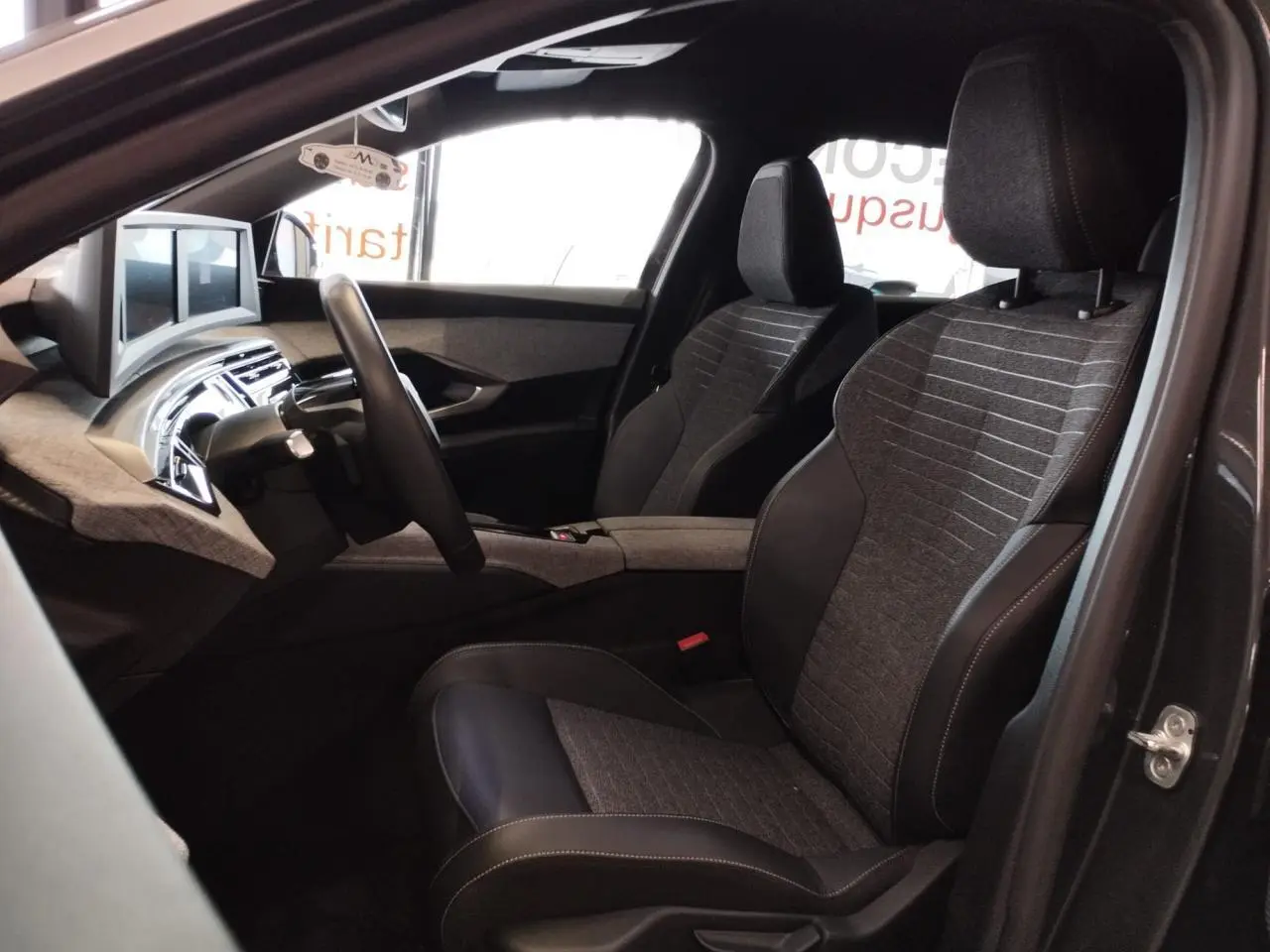 Vue intérieure côté conducteur du Peugeot 5008 gris titanium 2025, sièges tissu et cuir avec planche de bord moderne.