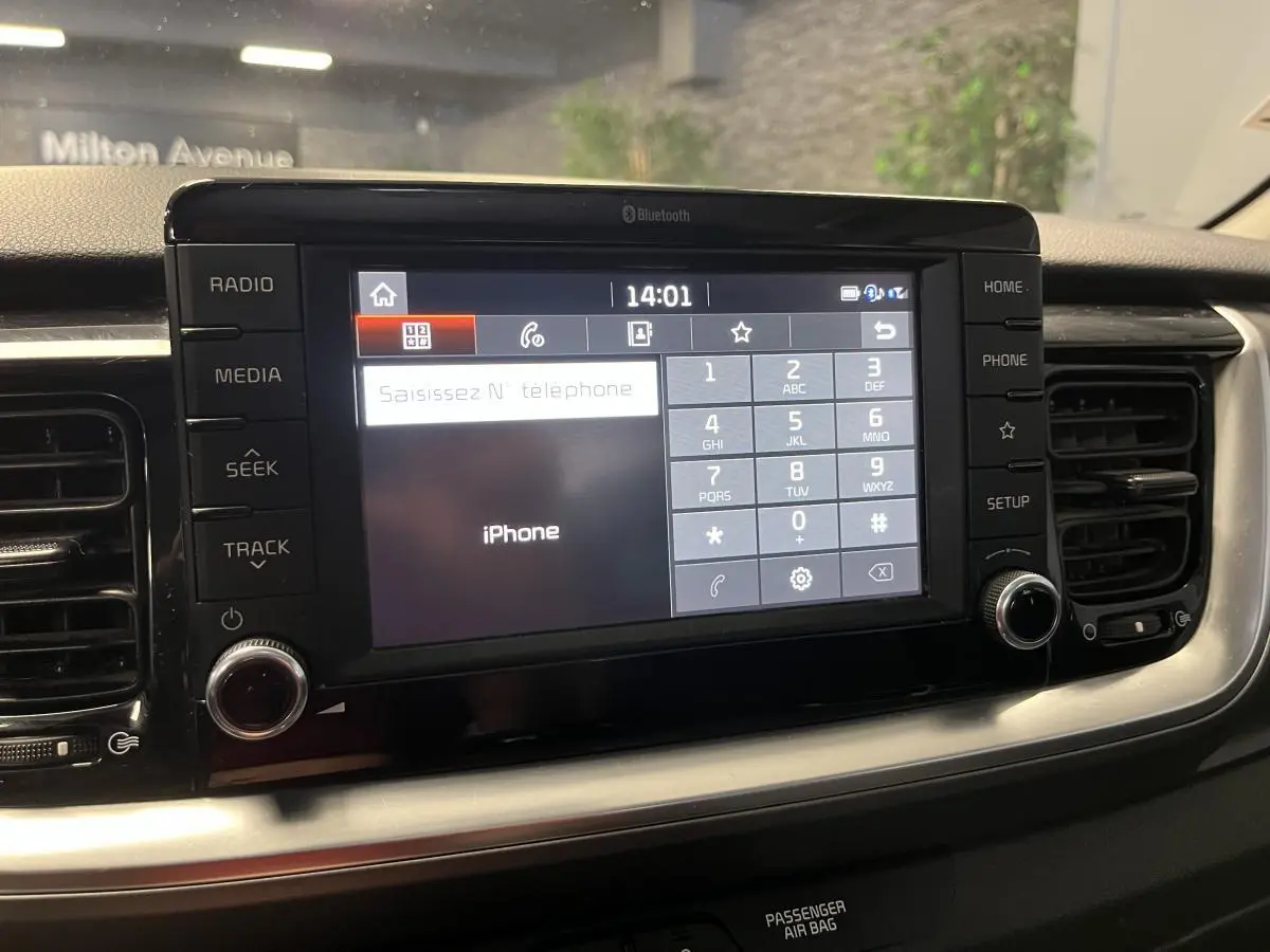 Écran tactile central du tableau de bord du Kia Stonic blanc 2019, avec interface Bluetooth et commandes autour.