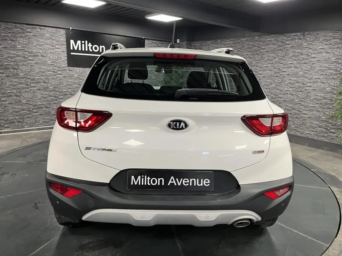 Vue arrière du KIA STONIC blanc de 2019 avec feux rouges et pare-chocs noir contrastant en intérieur showroom.
