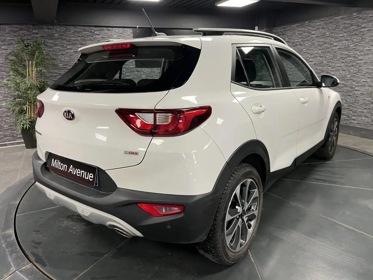 Vue 3/4 arrière droite d'un KIA Stonic blanc avec jantes alliage 17'' et protections noires sur les passages de roues.