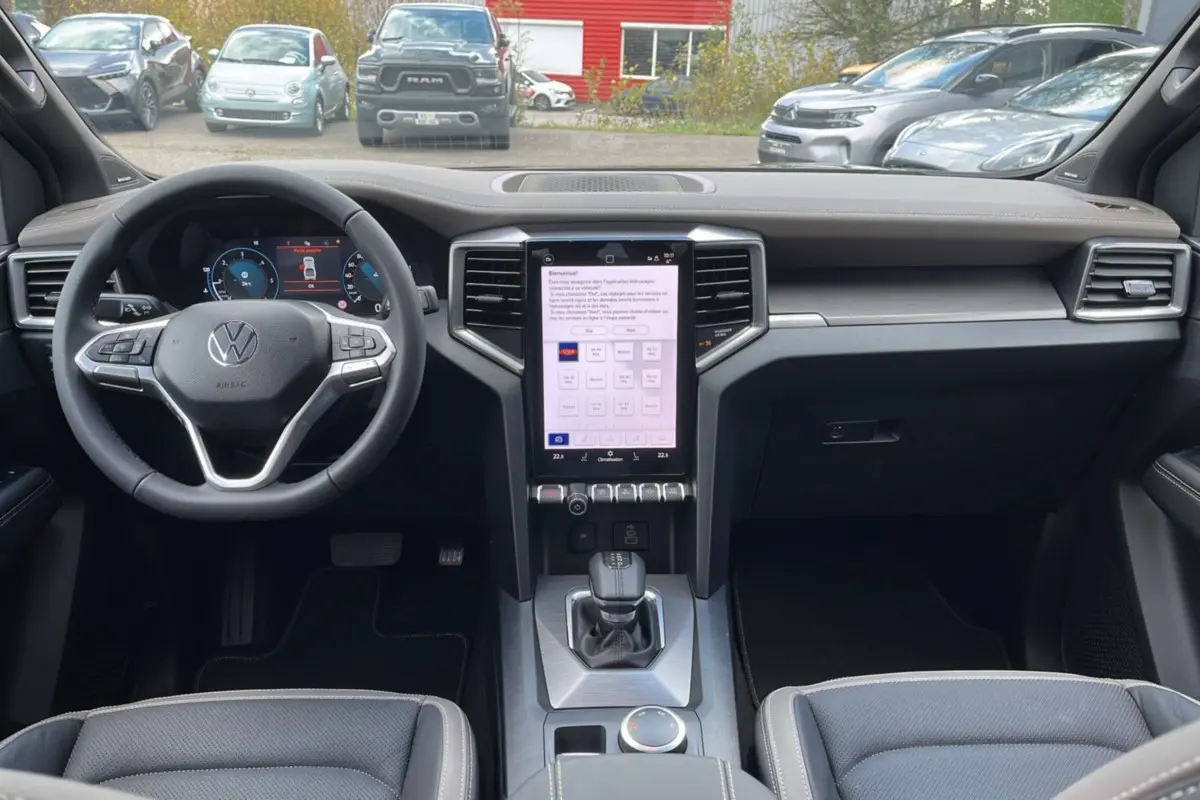 Vue intérieure du tableau de bord du Volkswagen Amarok Simple Cabine noir 2025 avec écran tactile vertical et volant multifonction.