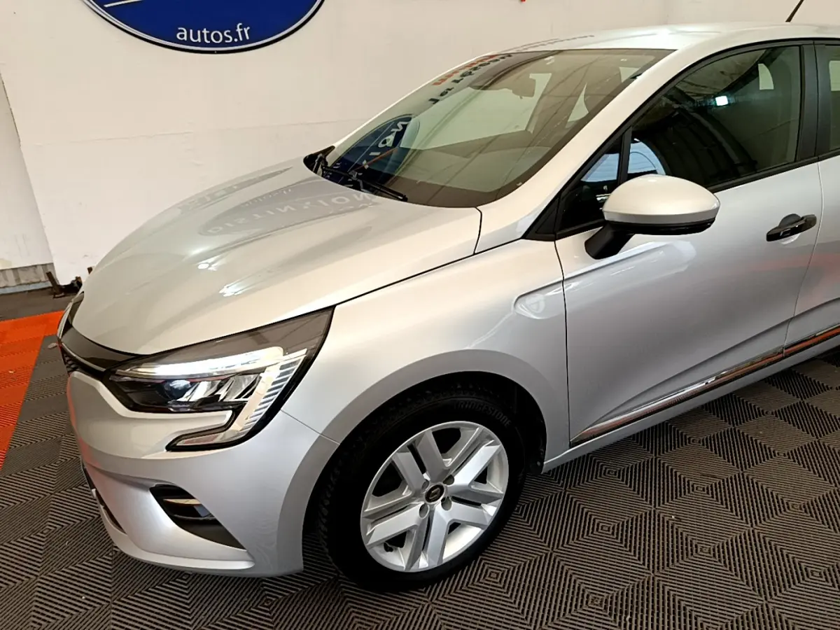 Vue 3/4 avant droit d'une Renault Clio Business TCe 100 gris clair avec phares LED et jantes alliage.