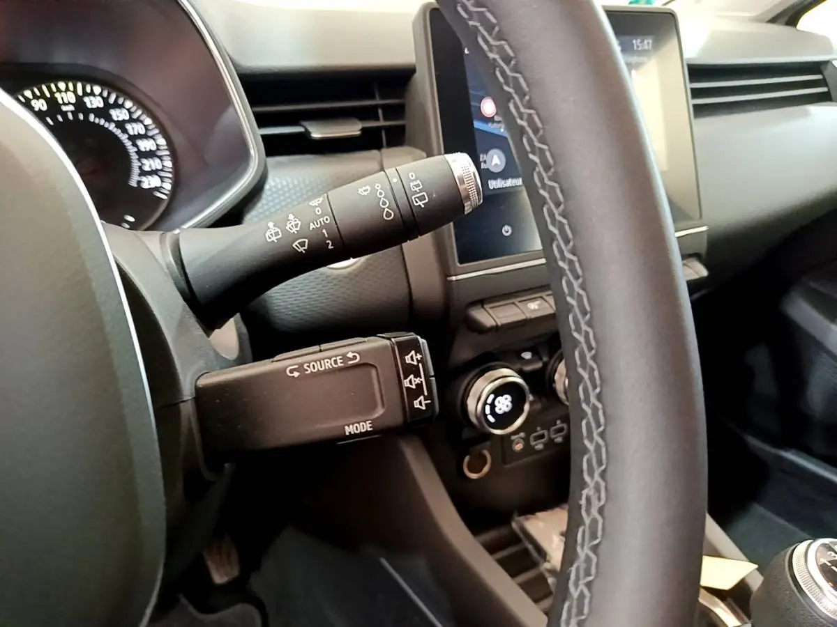 Vue rapprochée du volant et du tableau de bord de la Renault Clio Business TCe 100, avec commandes au volant et écran tactile.