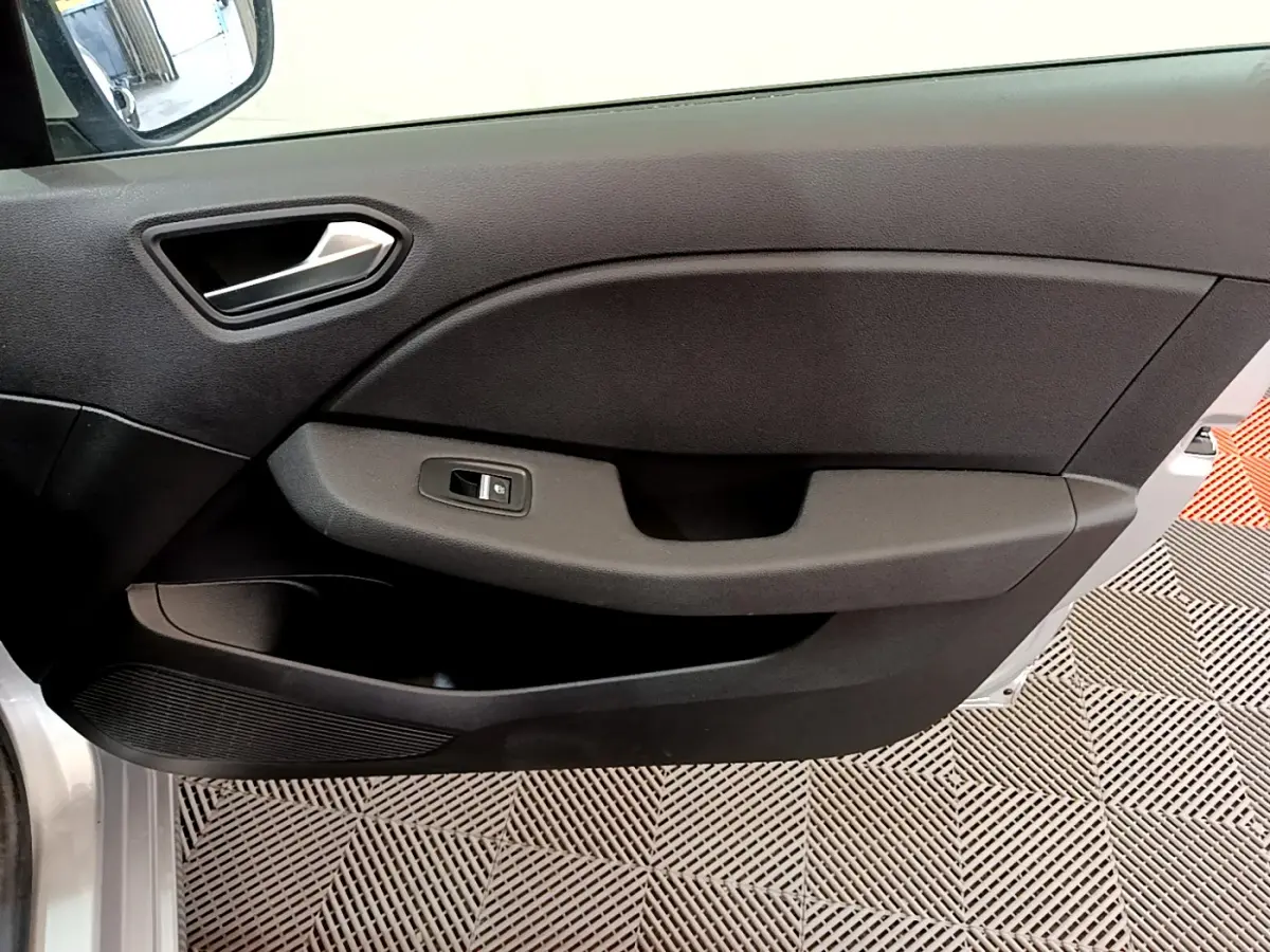 Vue intérieure du panneau de porte avant gauche de la Renault Clio Business TCe 100 gris clair, avec commande de fenêtre électrique.