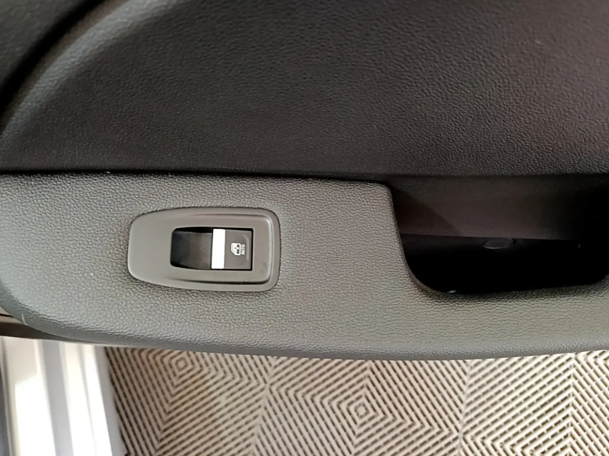 Gros plan sur le bouton de lève-vitre arrière droit dans l'habitacle gris clair d'une Renault Clio Business TCe 100 2020.