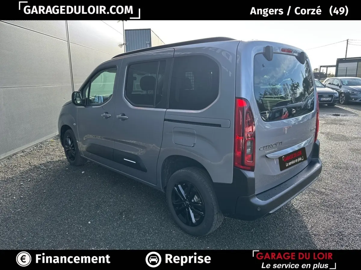 Vue 3/4 arrière droite d'un Citroën Berlingo gris clair avec vitres teintées et jantes noires.