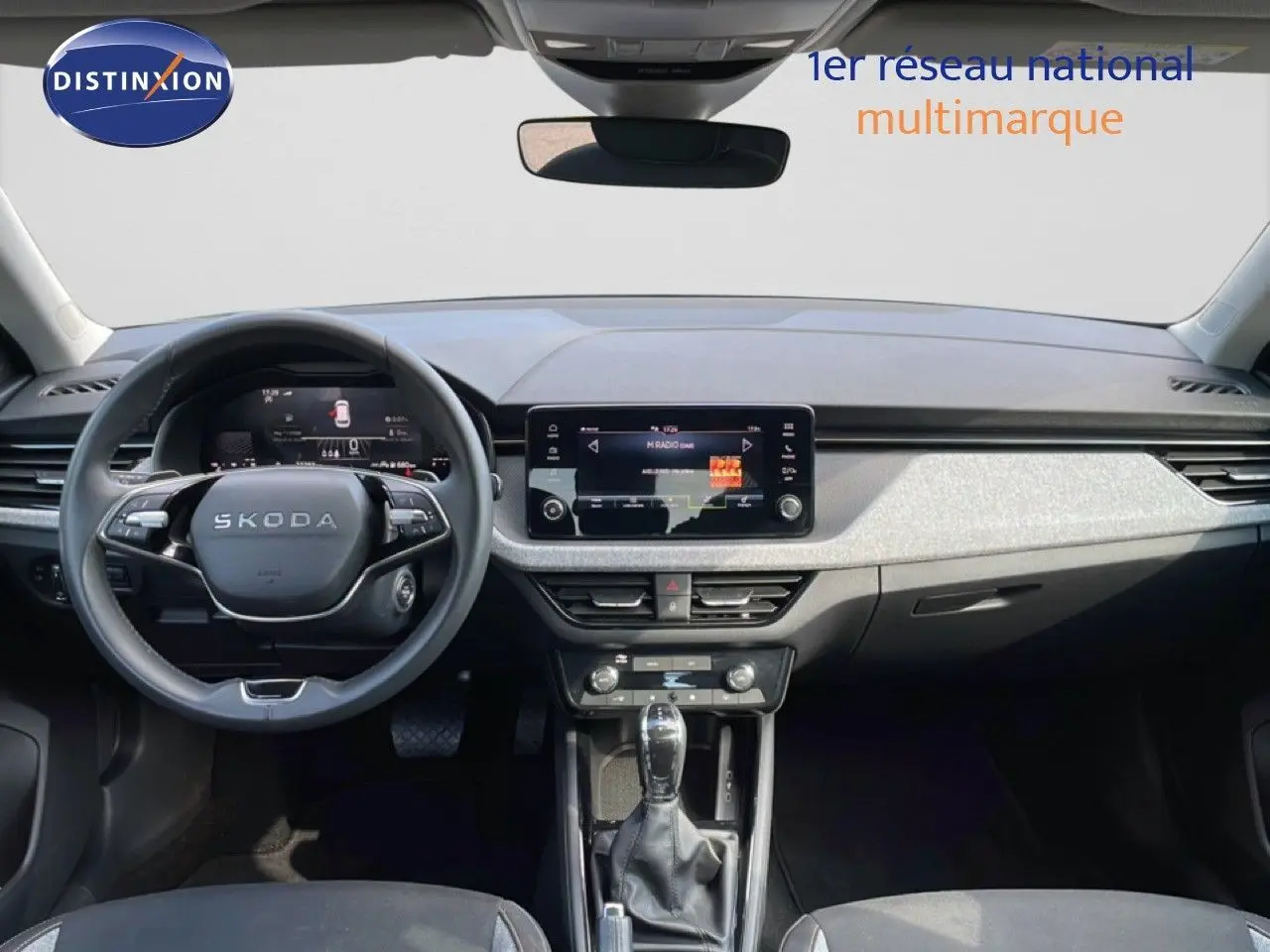Vue intérieure frontale du Skoda Kamiq gris argent métal 2025, mettant en valeur le tableau de bord et l’écran tactile central.