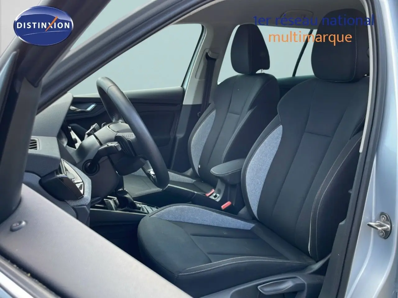 Vue intérieure côté gauche du Skoda Kamiq gris argent métal 2025, mettant en valeur les sièges avant en tissu noir et gris.