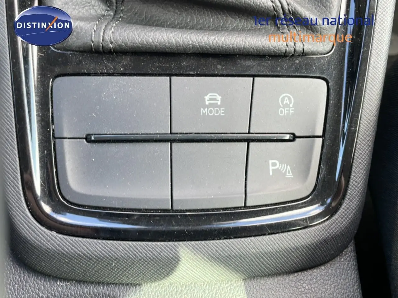 Gros plan sur les boutons de commande du mode de conduite et assistance au stationnement du Skoda Kamiq gris argent 2025.